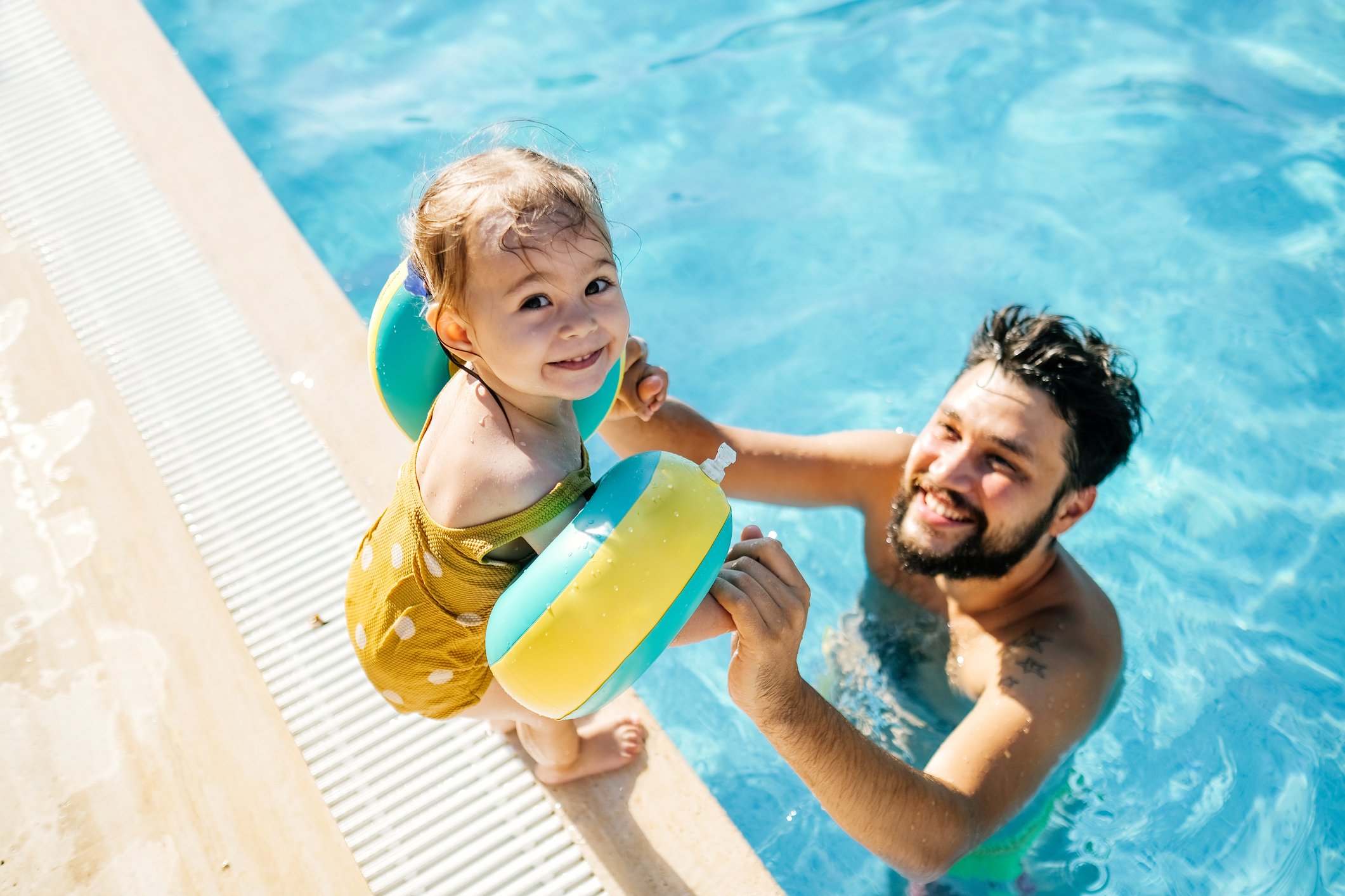Dad teaching daughter to swim at build-to-rent community pool