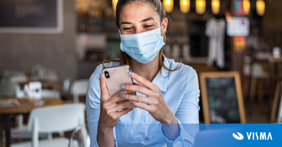 Portrait of a young business woman, wearing mask while making a mobile payment