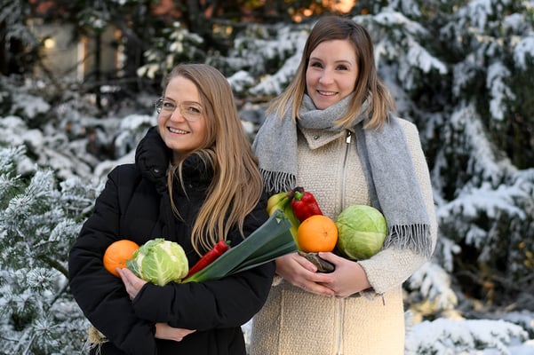 Tuulia Järvinen Venneriltä ja Hanna Siimes POP Pankilta pitelevät sylissään kasviksia, jotka sisältyvät Vennerin ruokalaatikkoon.