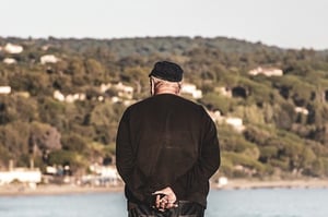 Older man outdoors looking at body of water
