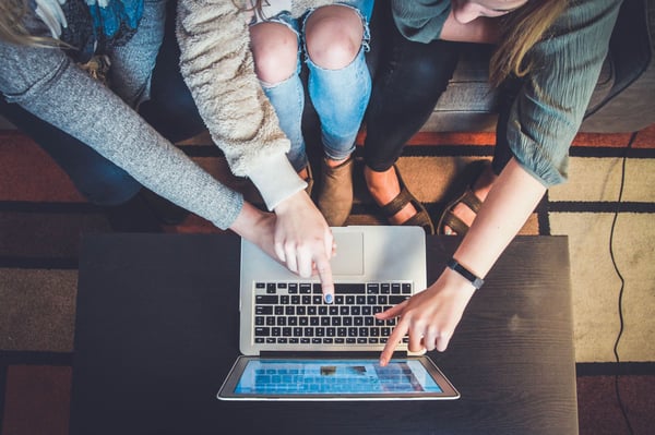 A group of people using a laptop, seen from above