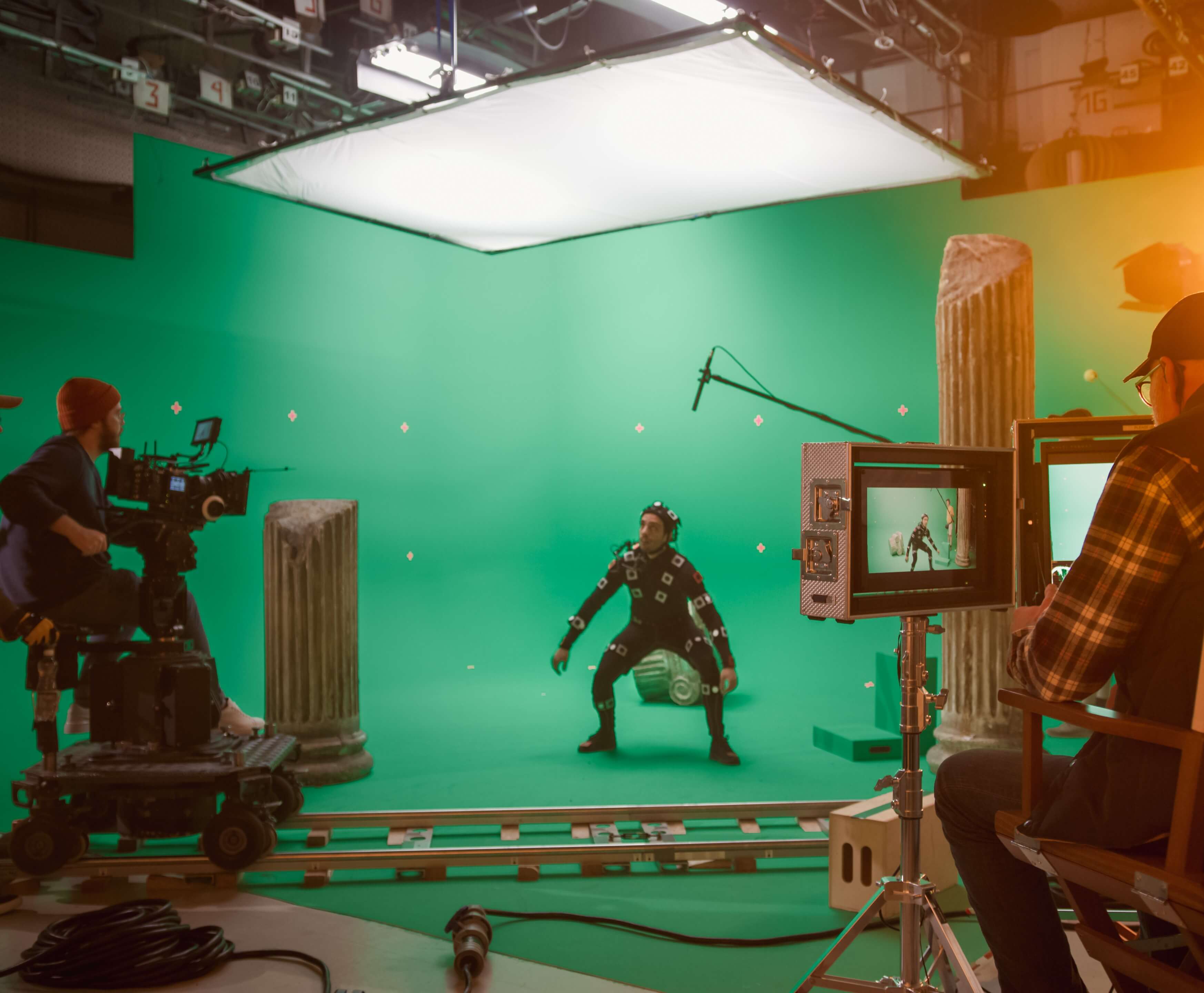 In-the-Big-Film-Studio-Professional-Crew-Shooting-Blockbuster-Movie.-Director-Commands-Cameraman-to-Start-shooting-Green-Screen-CGI-Scene-with-Actor-Wearing-Motion-Capture-Suit-and-Head-Rig-1265157445_5120x2880