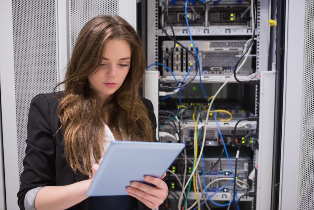 Woman using tablet pc in front of servers in data center