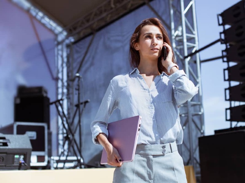 administracion_de_empresas_de_entretenimiento_mujer_joven_habla_por_telefono_con_escenario_detras