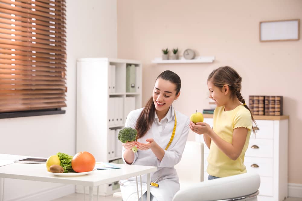 licenciatura-en-nutricion-doctora-joven-enseña-alimentos-a-niña