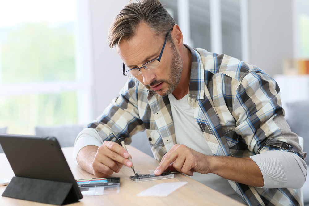 Man at home fixing smartphone with assistance of internet