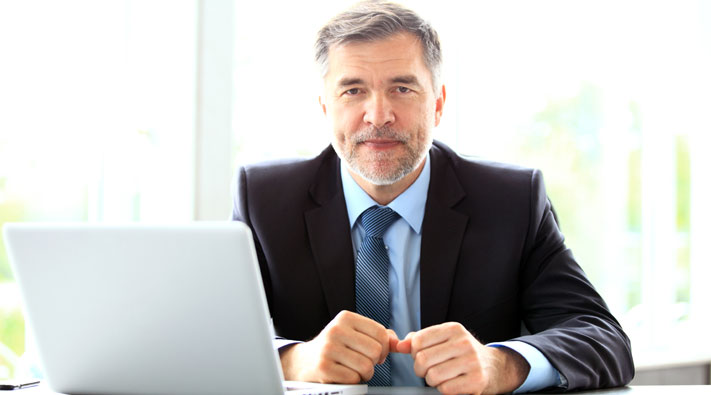 A man in the suit in front of a laptop