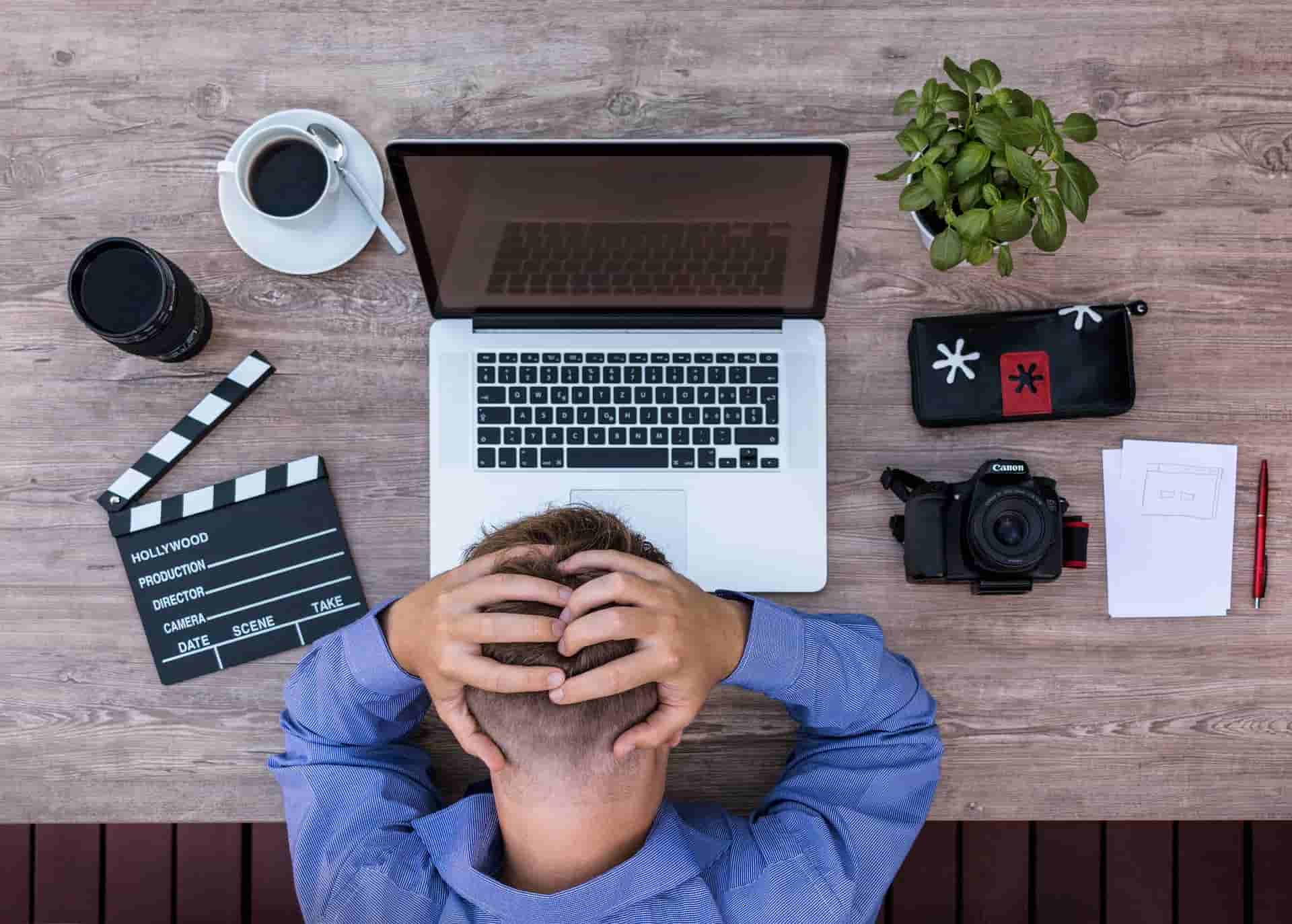 Frustrated person sitting at desk surrounded by equipment