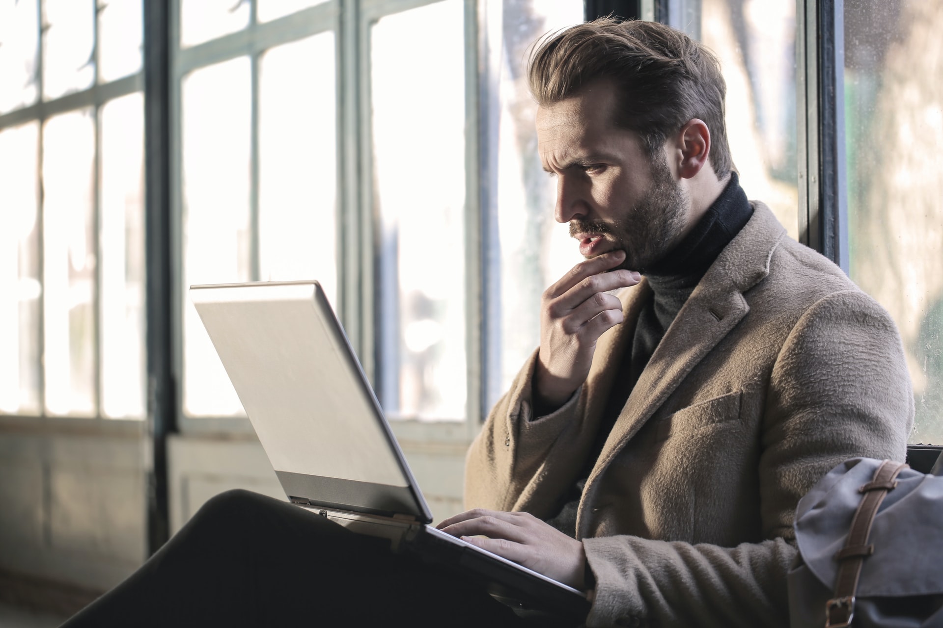 Man holding his chin holding a laptop