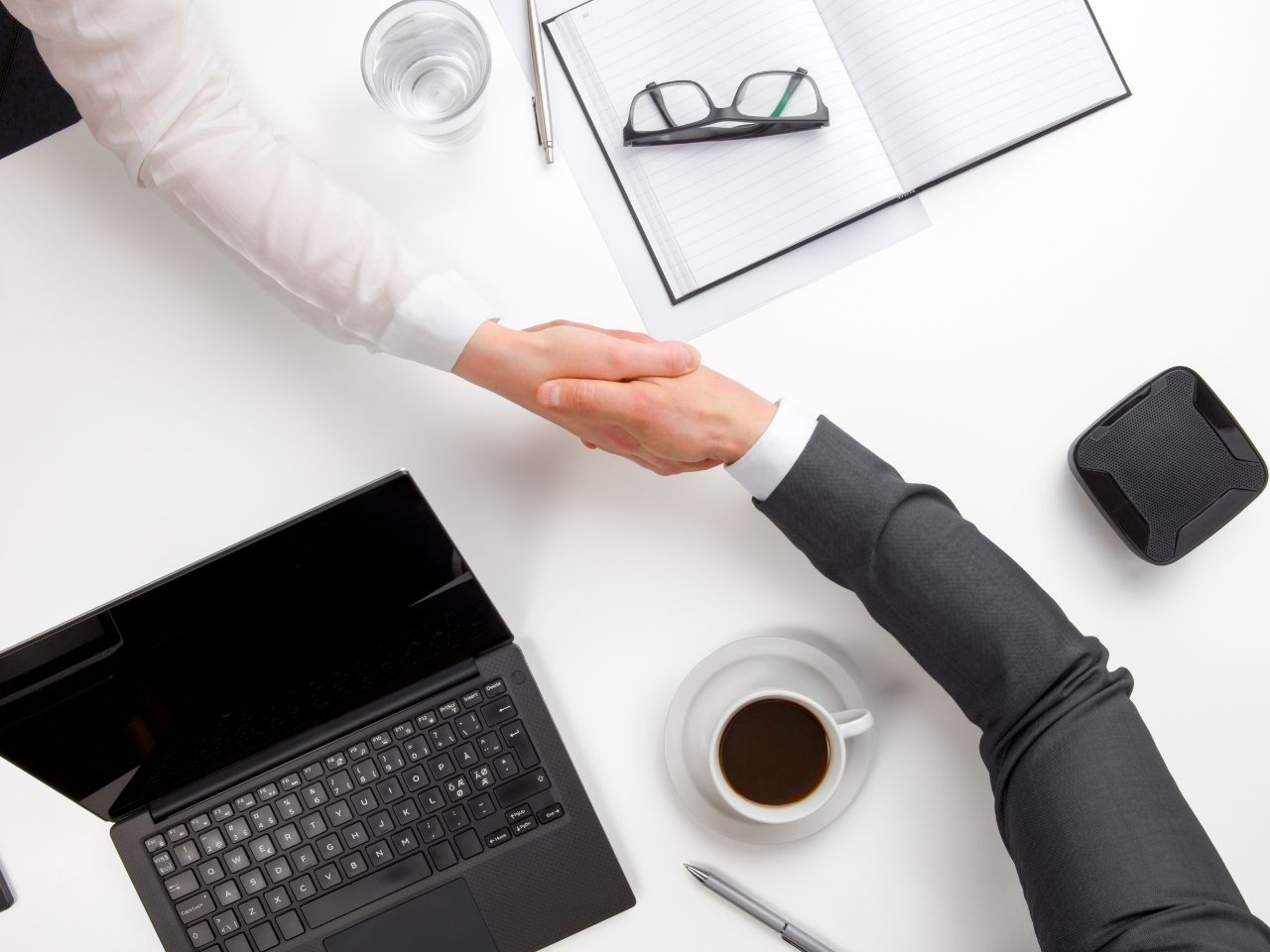 Men shaking hands over white desk