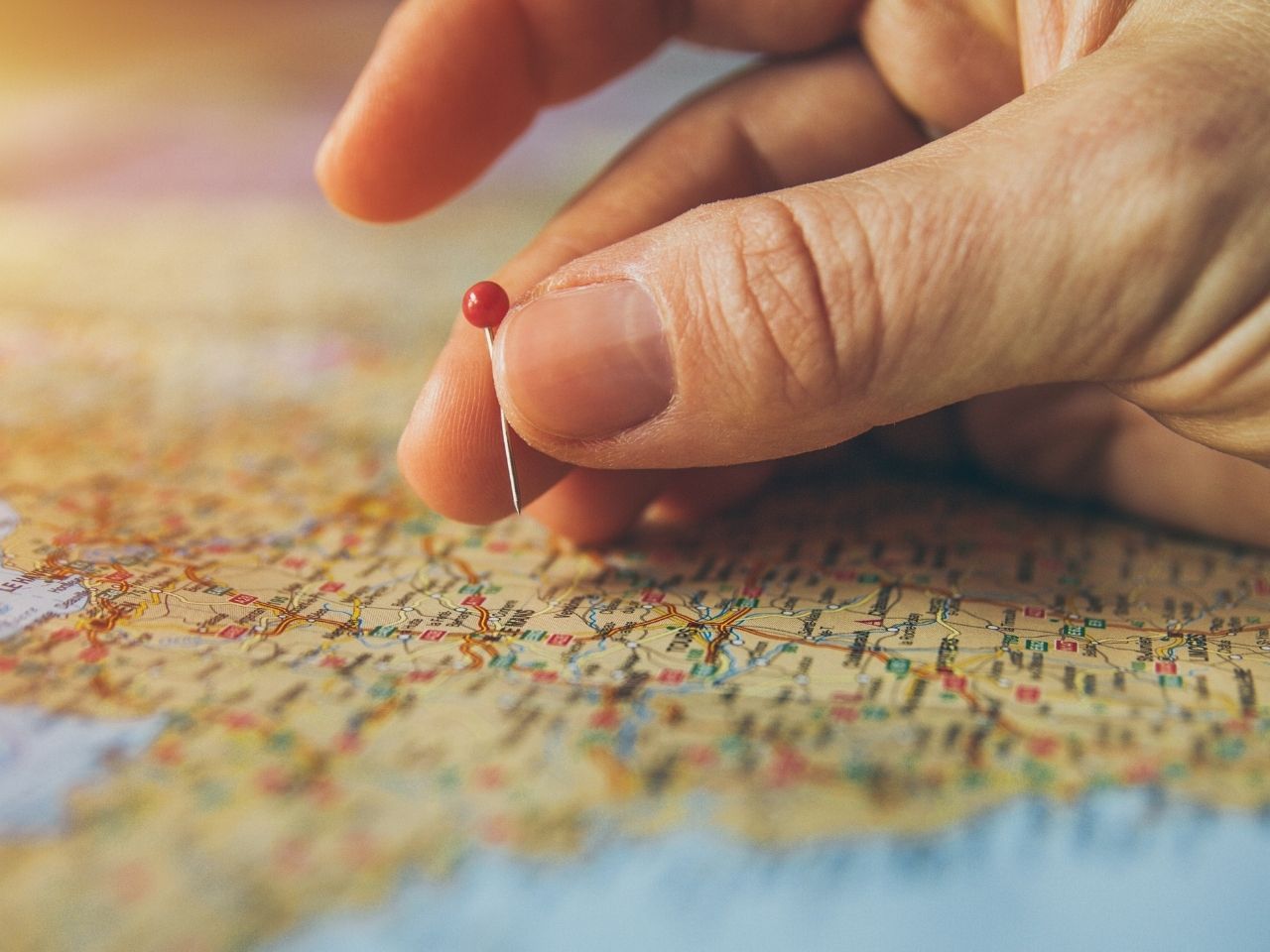 Man using a red pin point on a map