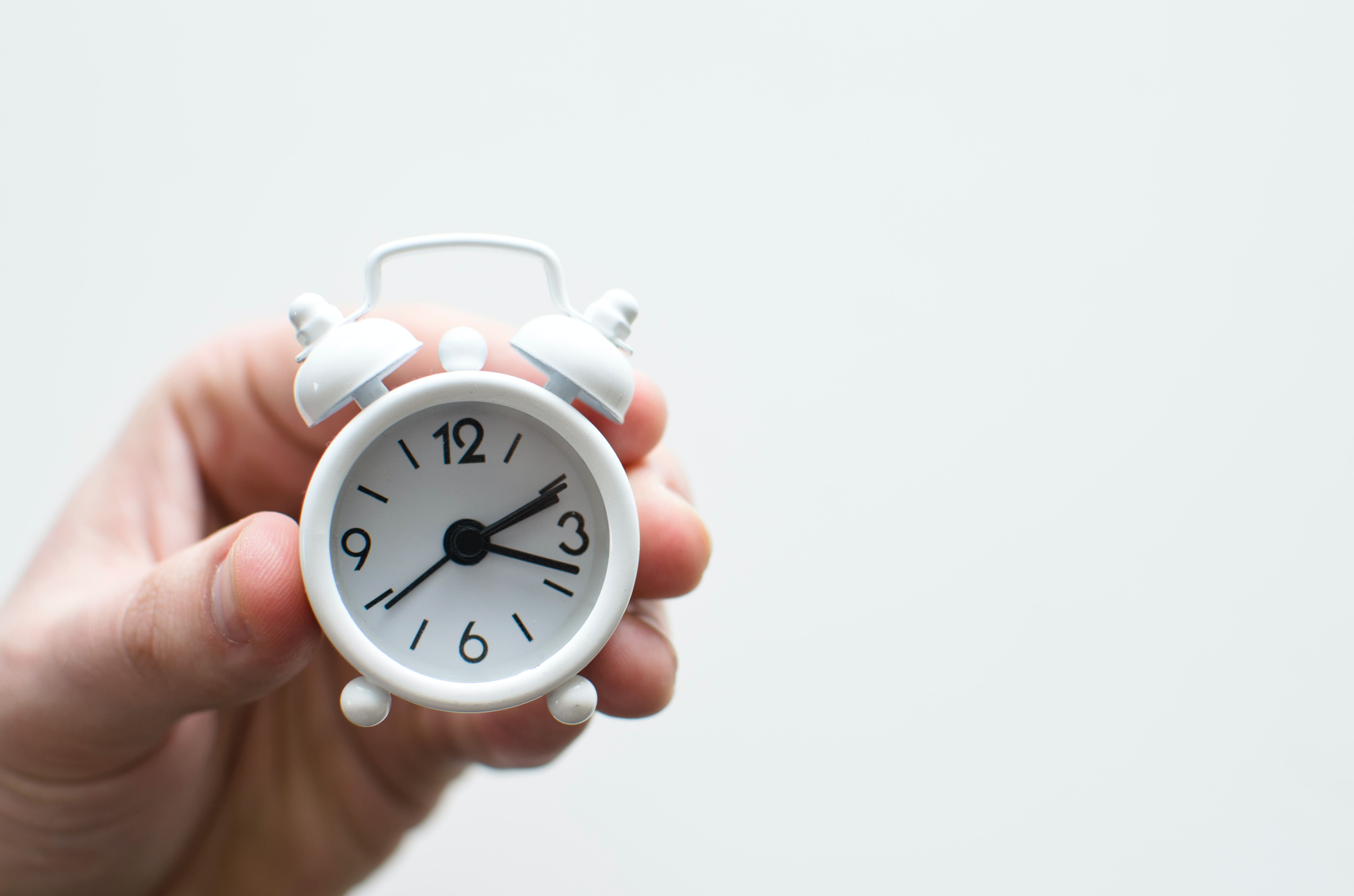 Person holding little alarm clock