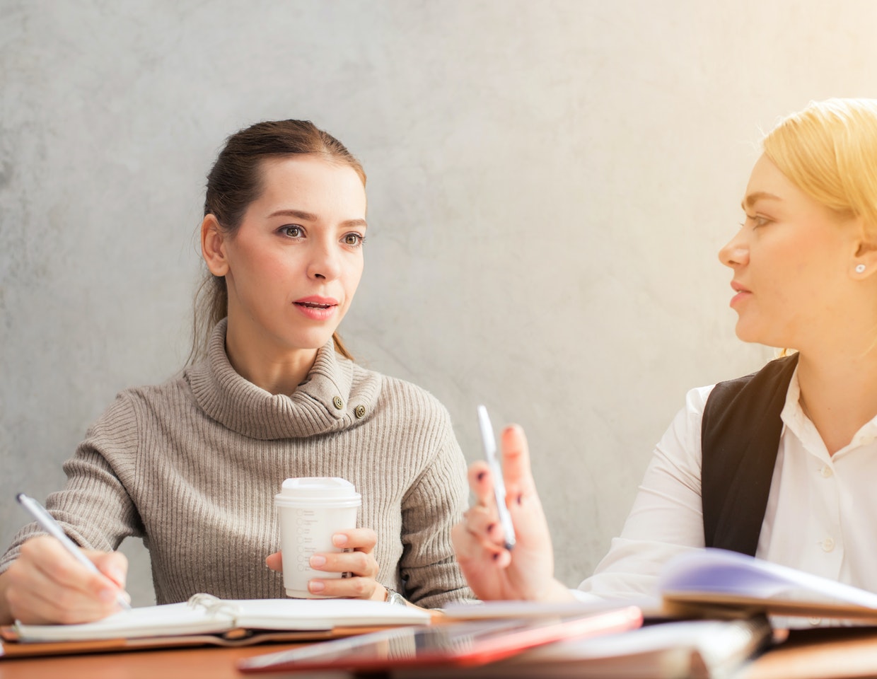 Two women discussing and holding pencils