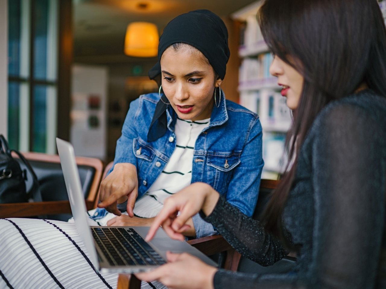 Two women pointing on a laptop