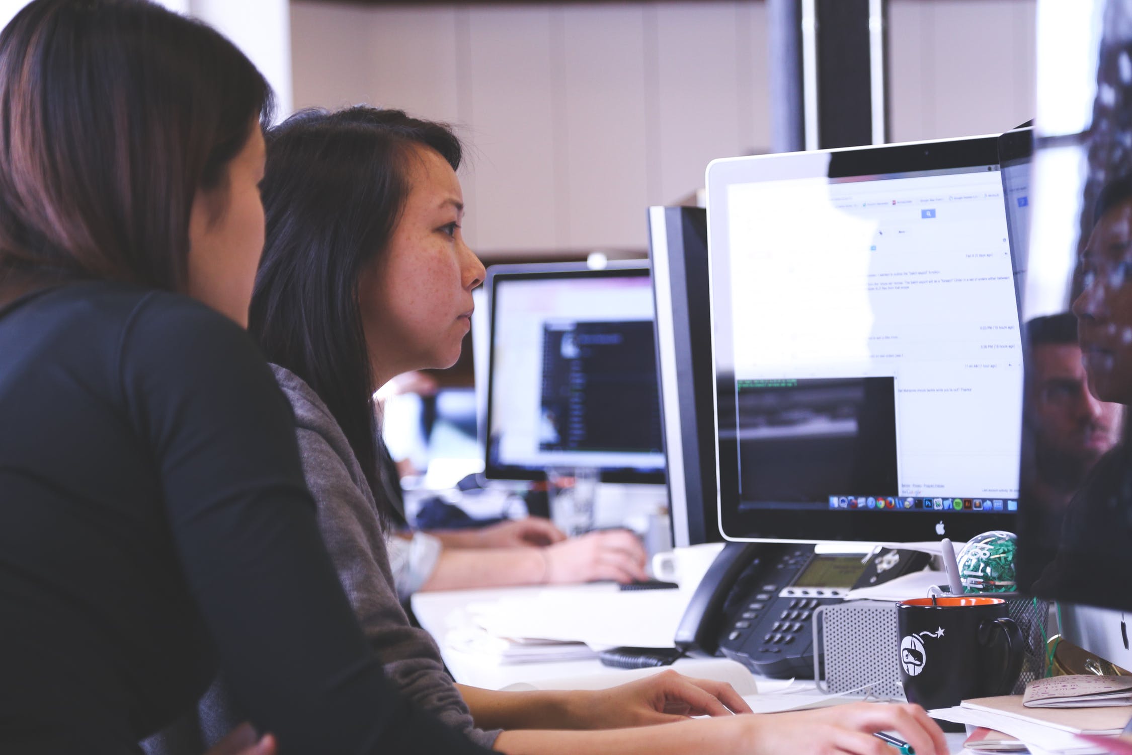 Two women staying in front of a desktop