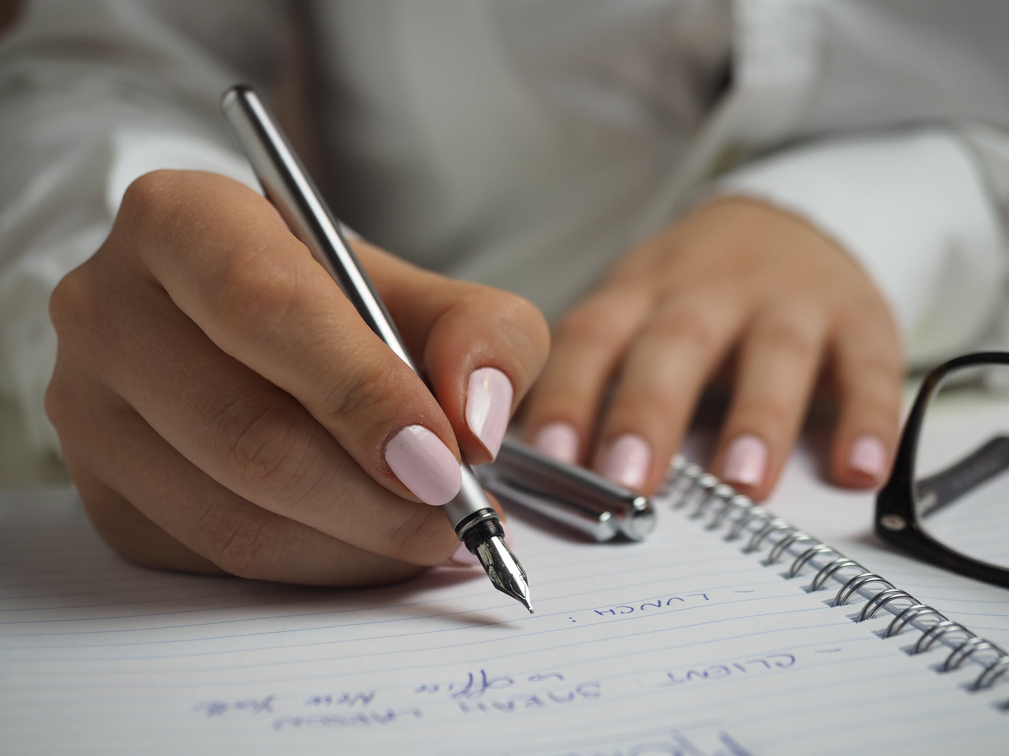 Woman with pink nails writing a list