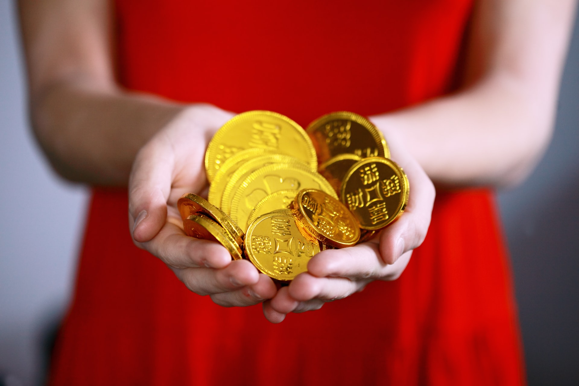 Woman dressed in red holding gold coins