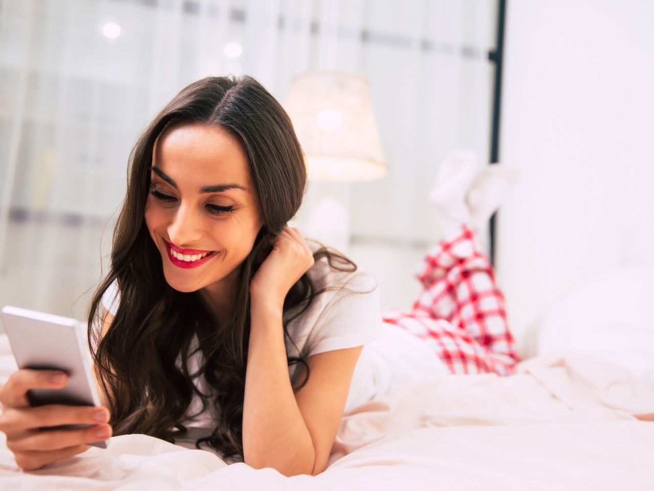 Woman using phone on bed