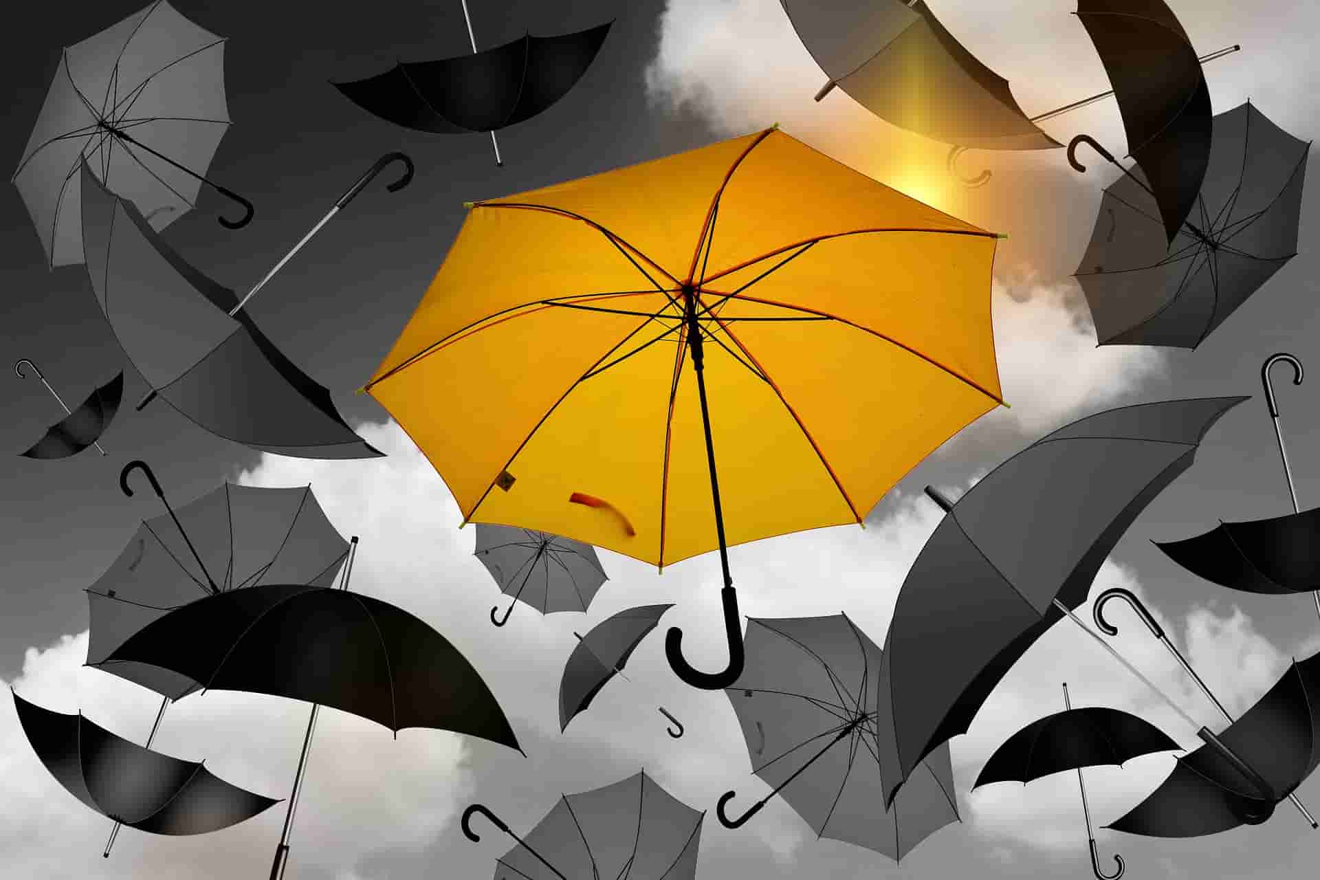 Yellow umbrella standing out from gray background