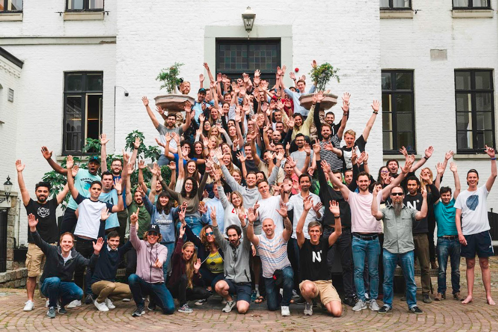 It's a picture of the entire Nmbrs team. Everyone is together, looking at the camera, with their arms raised high.