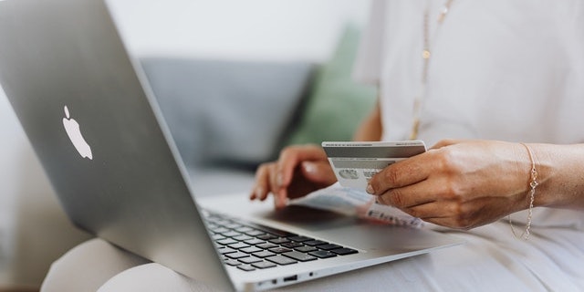 hand-holding-credit-card-near-computer