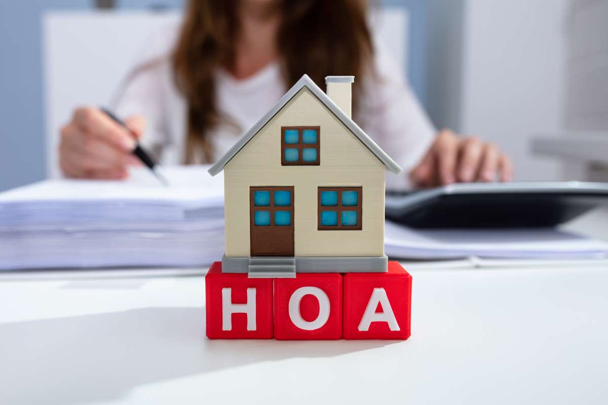 Close-up Of House Model Over HOA Blocks In Front Of Businesswoman (R) (S)