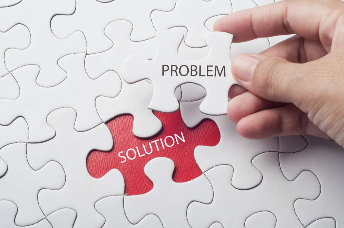 Hand holding piece of jigsaw puzzle with word problem & solution