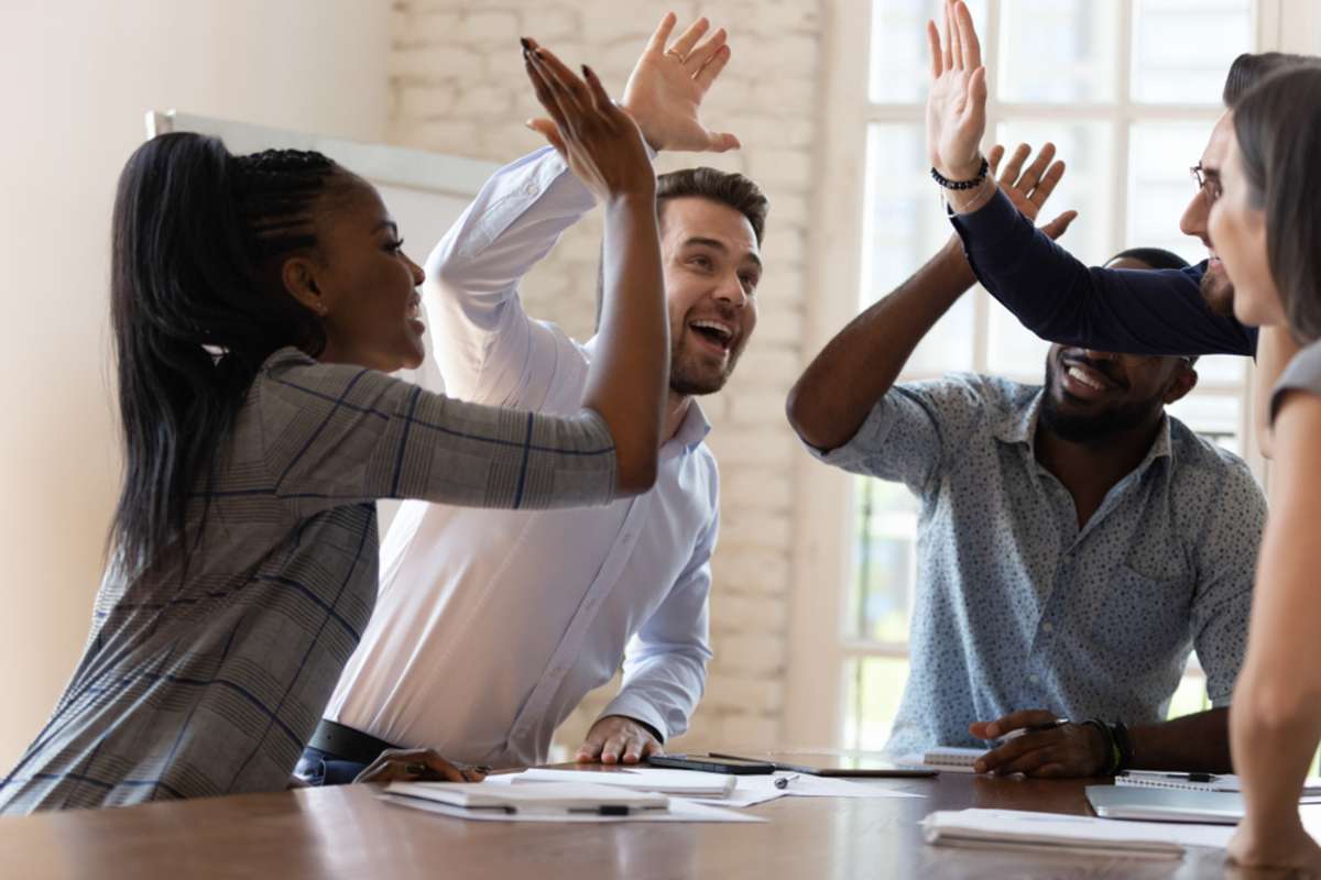 Multiracial euphoric business team people give high five at office table