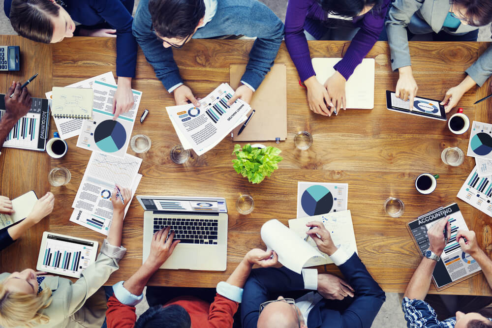 Employees at a table discussing possible actions for a business | NameCorp