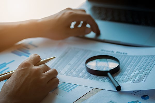 Magnifying glass on top of financial data papers