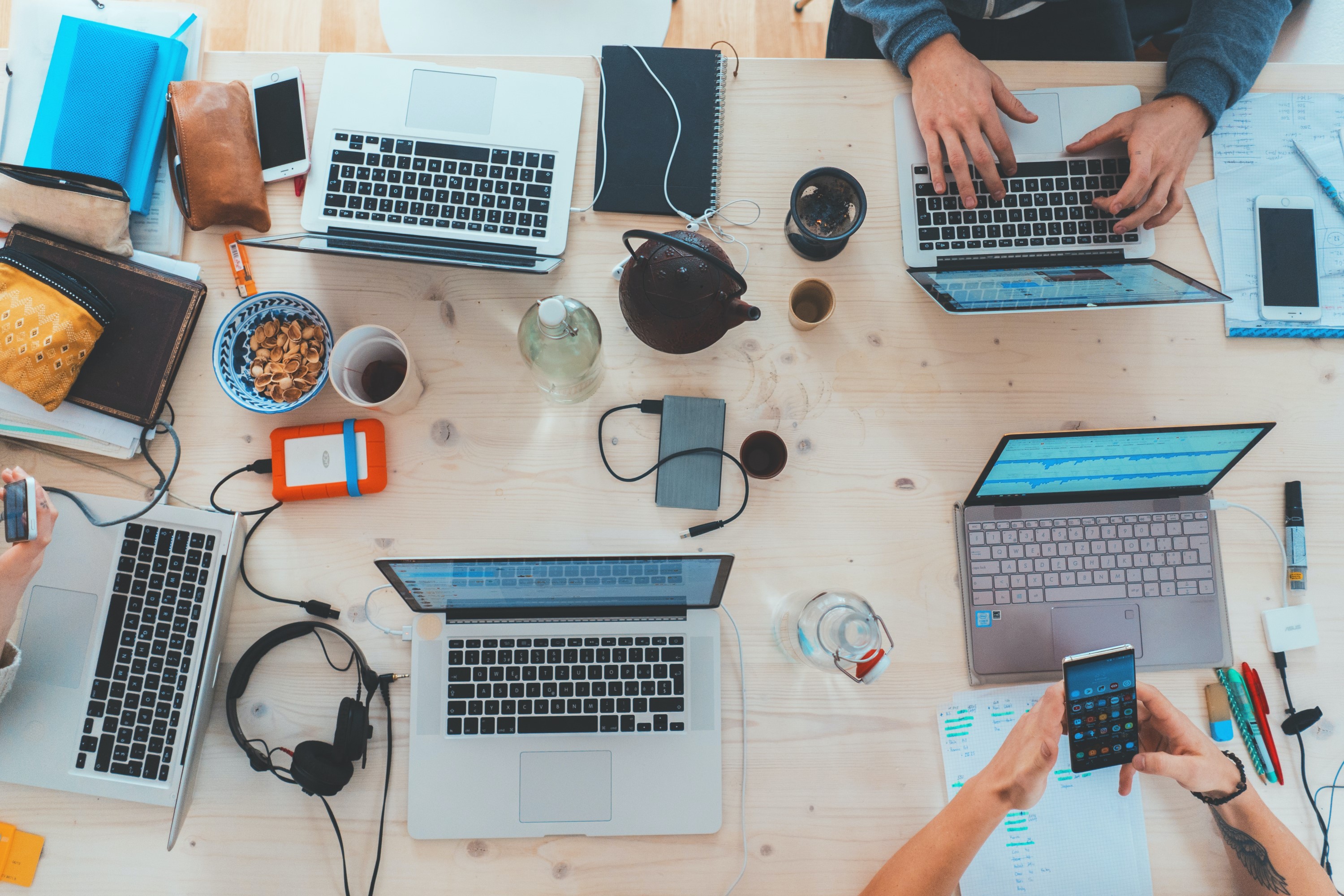 Laptops, phones drinks and snacks on a wooden table 