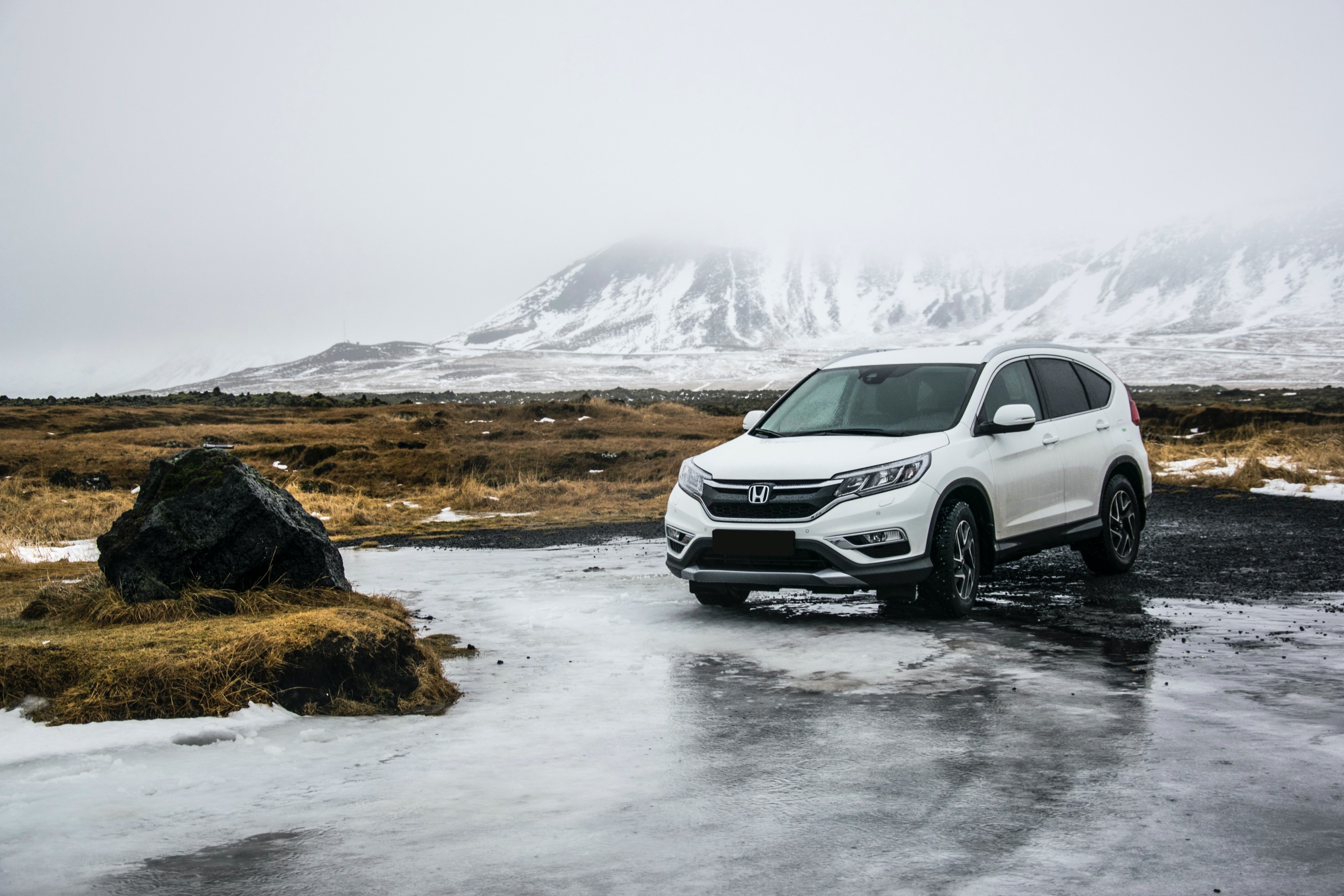 white car in wildlands with snowy mountains in the back